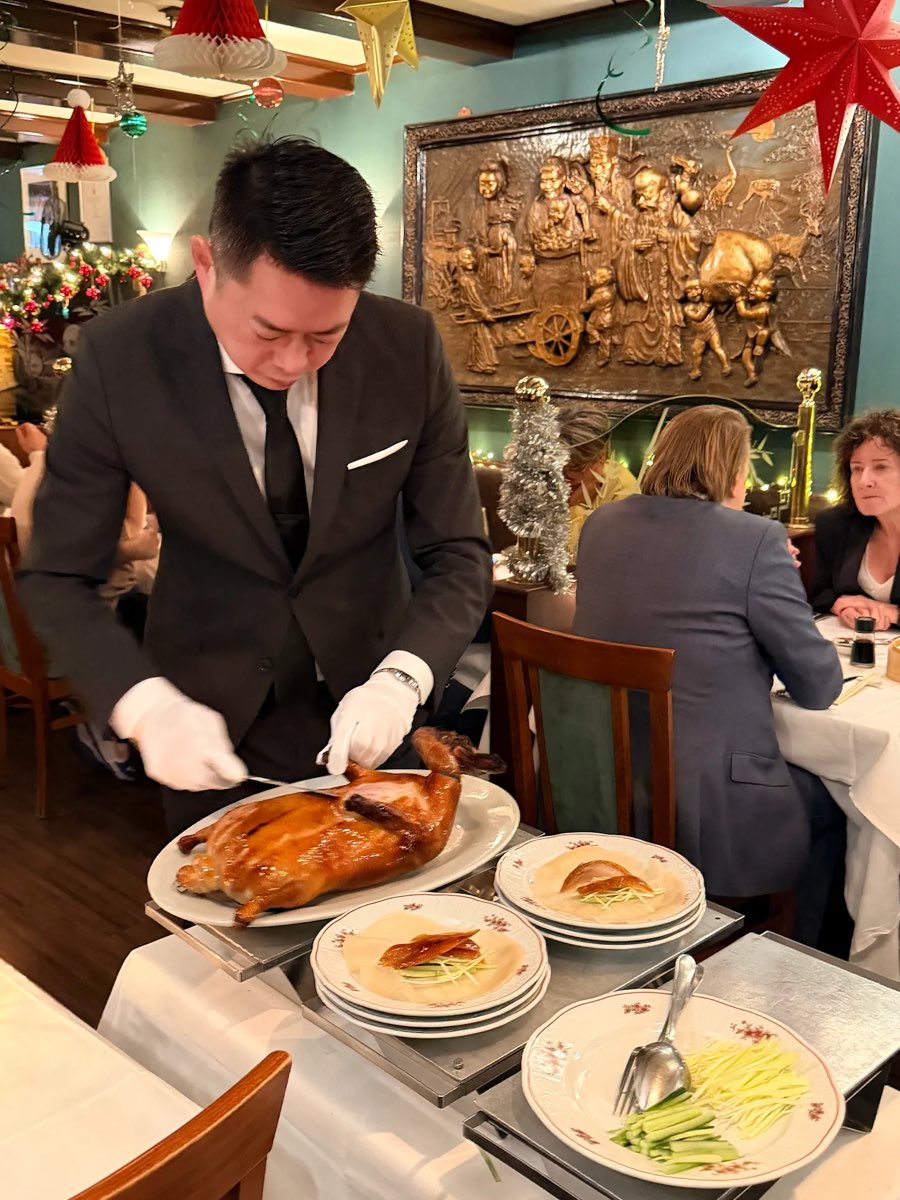 Ober snijdt de Peking eend aan tafel